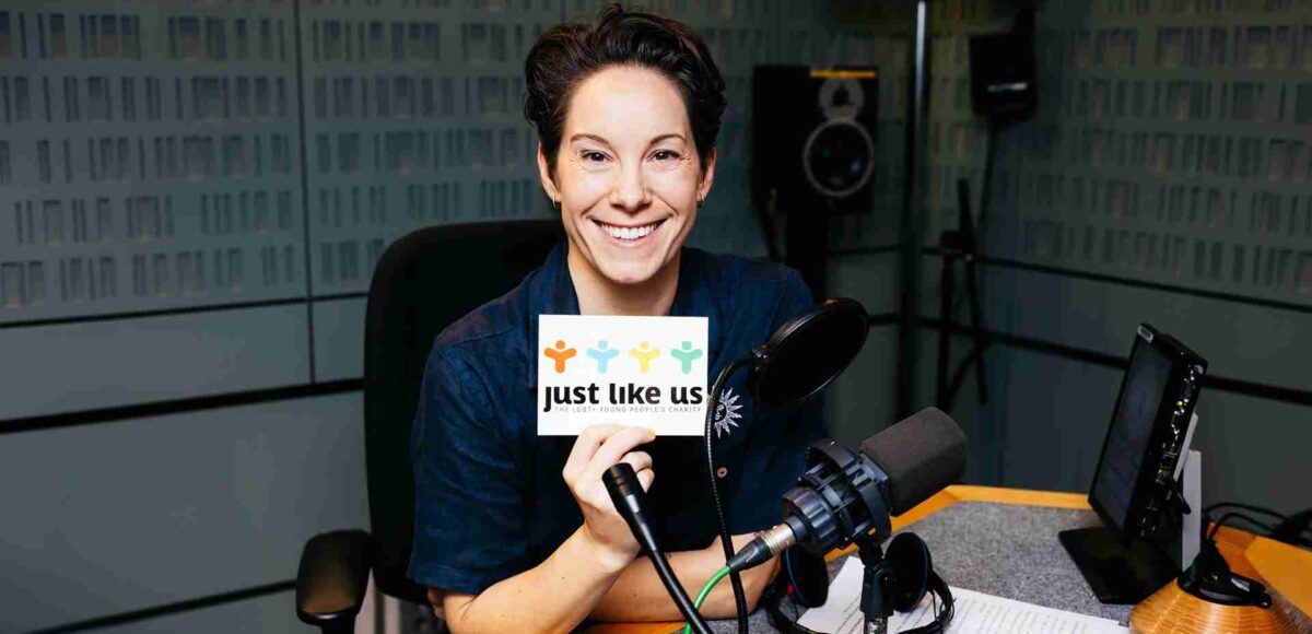 Suzi Ruffell holding up a Just Like Us postcard with her script