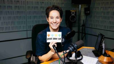 Suzi Ruffell holding up a Just Like Us postcard with her script
